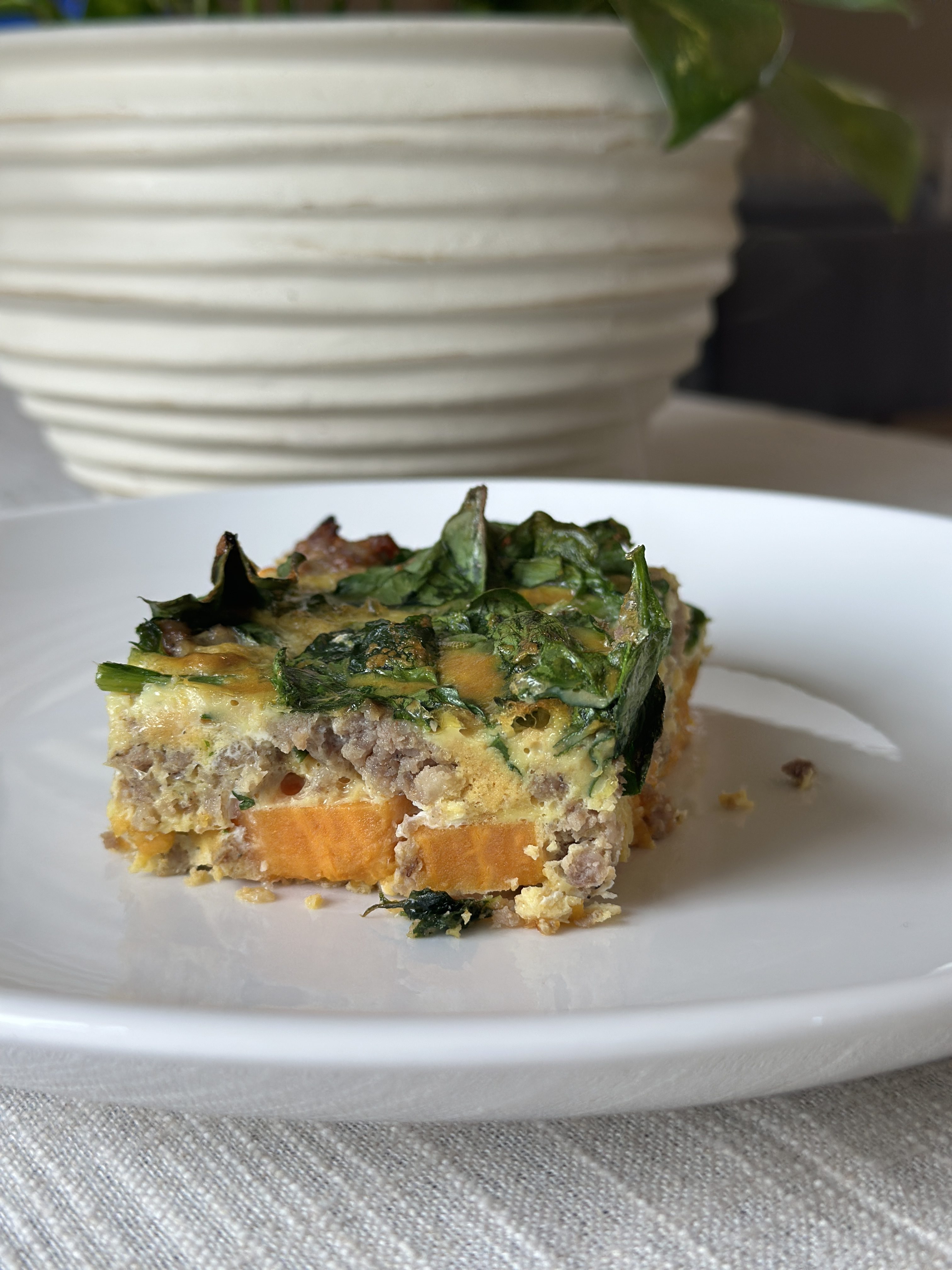 Easy sweet potato breakfast casserole with sausage, spinach, and eggs baked in a casserole dish.